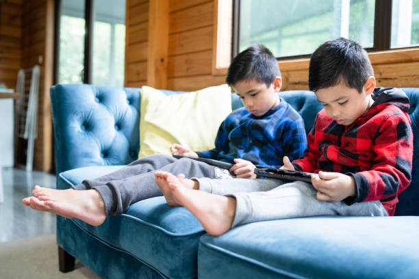 Kids' Screen Time Australia Mixed race kids at home using smart tablets to play games.