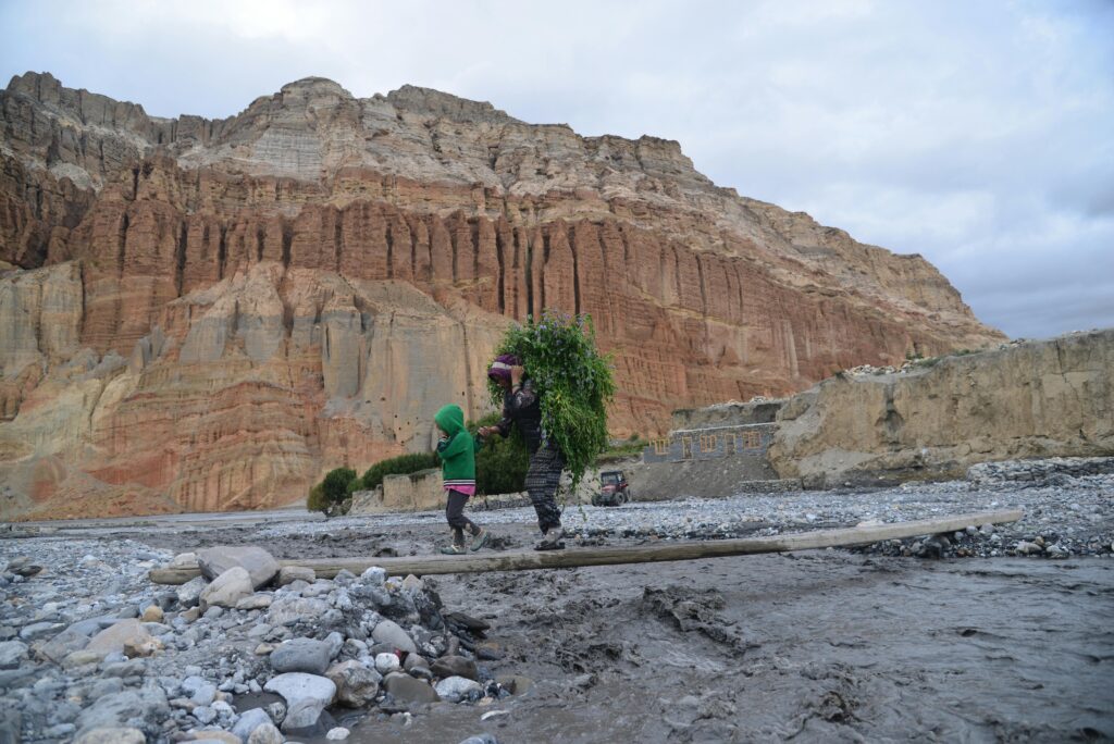 A Child and a Woman Walking in the Valley near a Large Cliff in Chhusang Village, Nepal